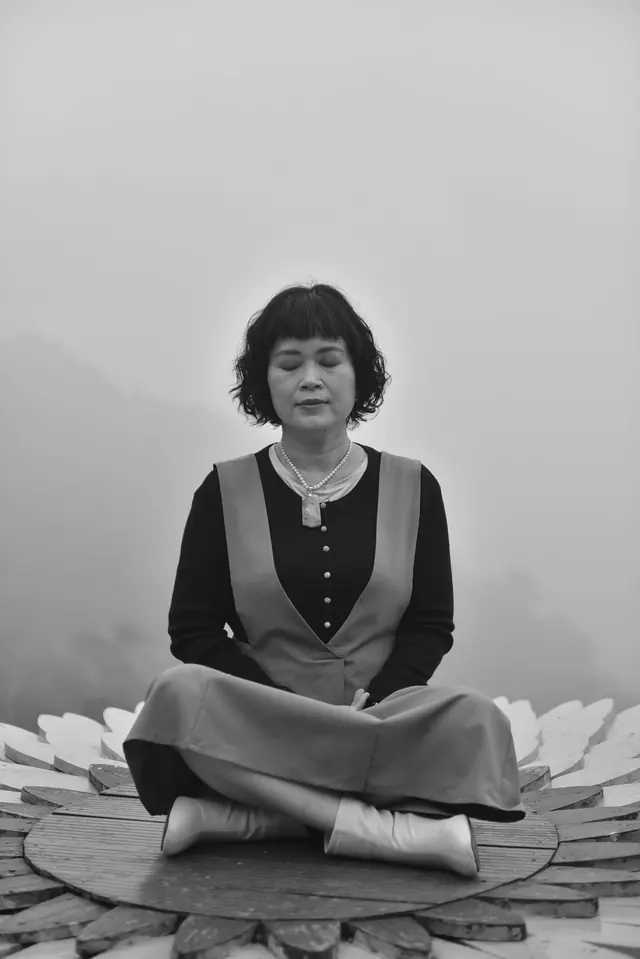 A woman meditating on a lotus platform in a misty, serene setting